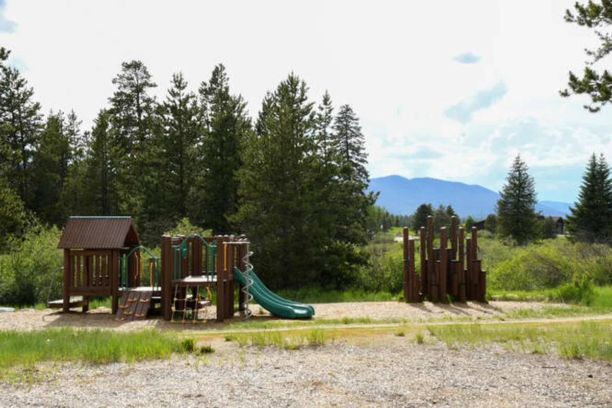 A lively outdoor playground with slides and climbing features, surrounded by natural elements, filled with children and families enjoying active outdoor play. The setting is energetic and family-friendly, suggesting a range of adventures available nearby.